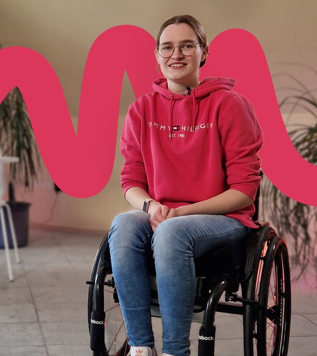 Lea Habekost sitzt im Rollstuhl, daneben auf einem Stuhl ihr Exoskelett.