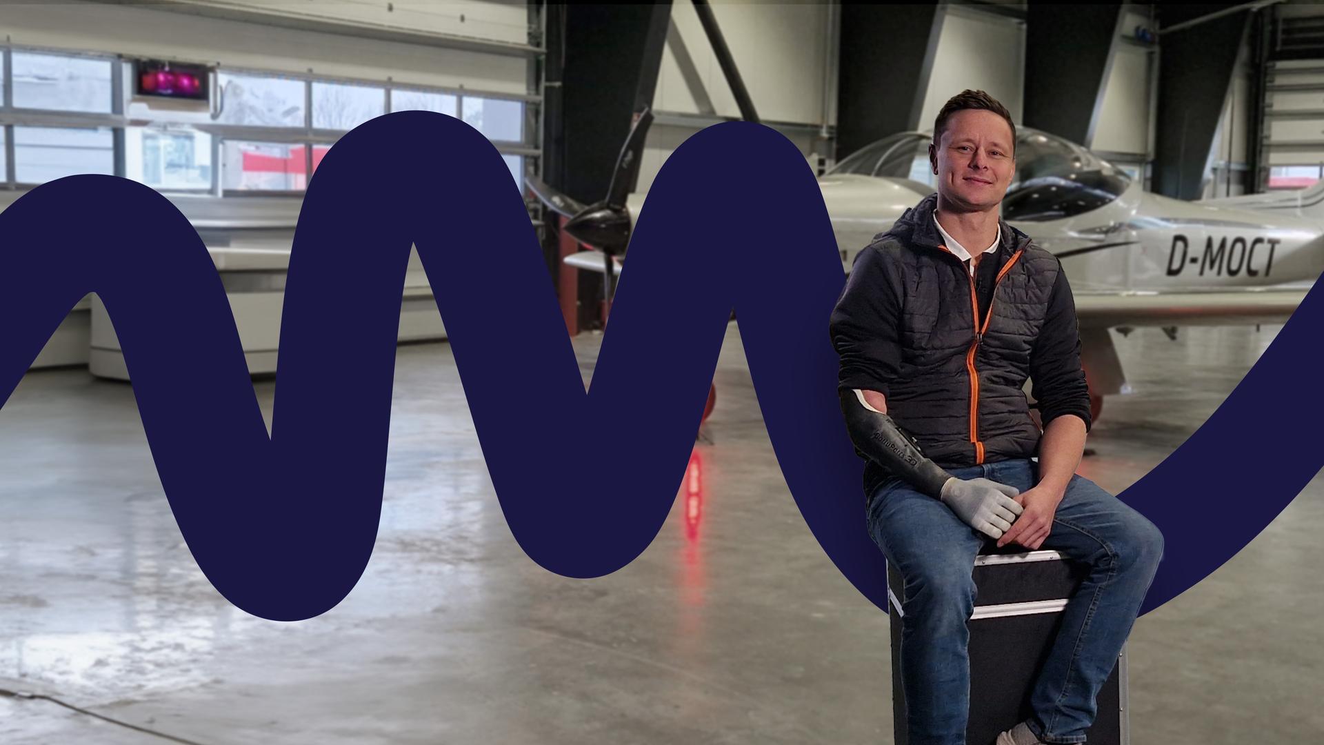 Philipp Barluschke in einem Flugzeughanger, im Hintergrund eine Sportmaschine.
