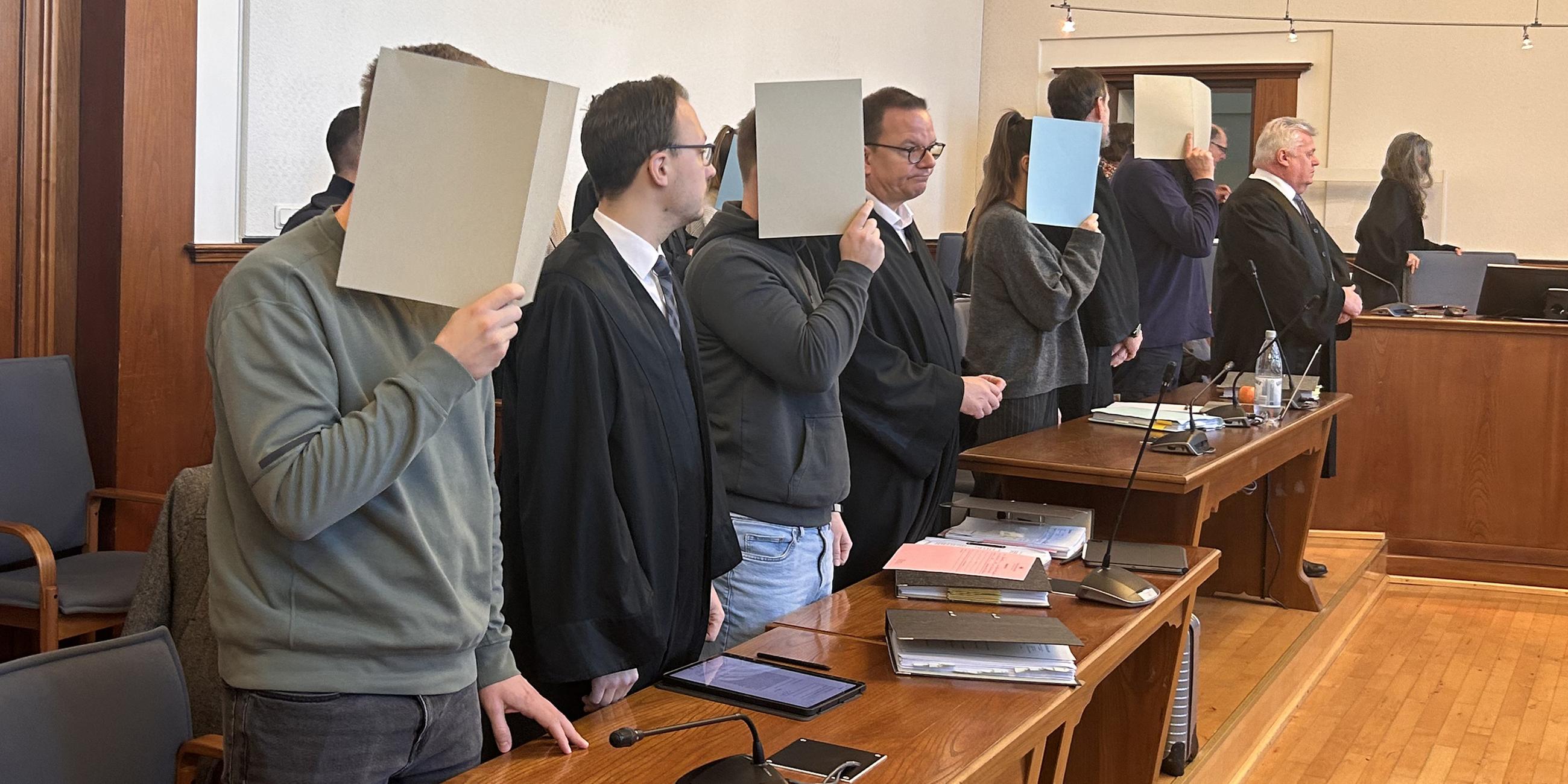 Die Angeklagten verdecken ihre Gesichter am 06.03.2024 im Gerichtssaal in Dortmund