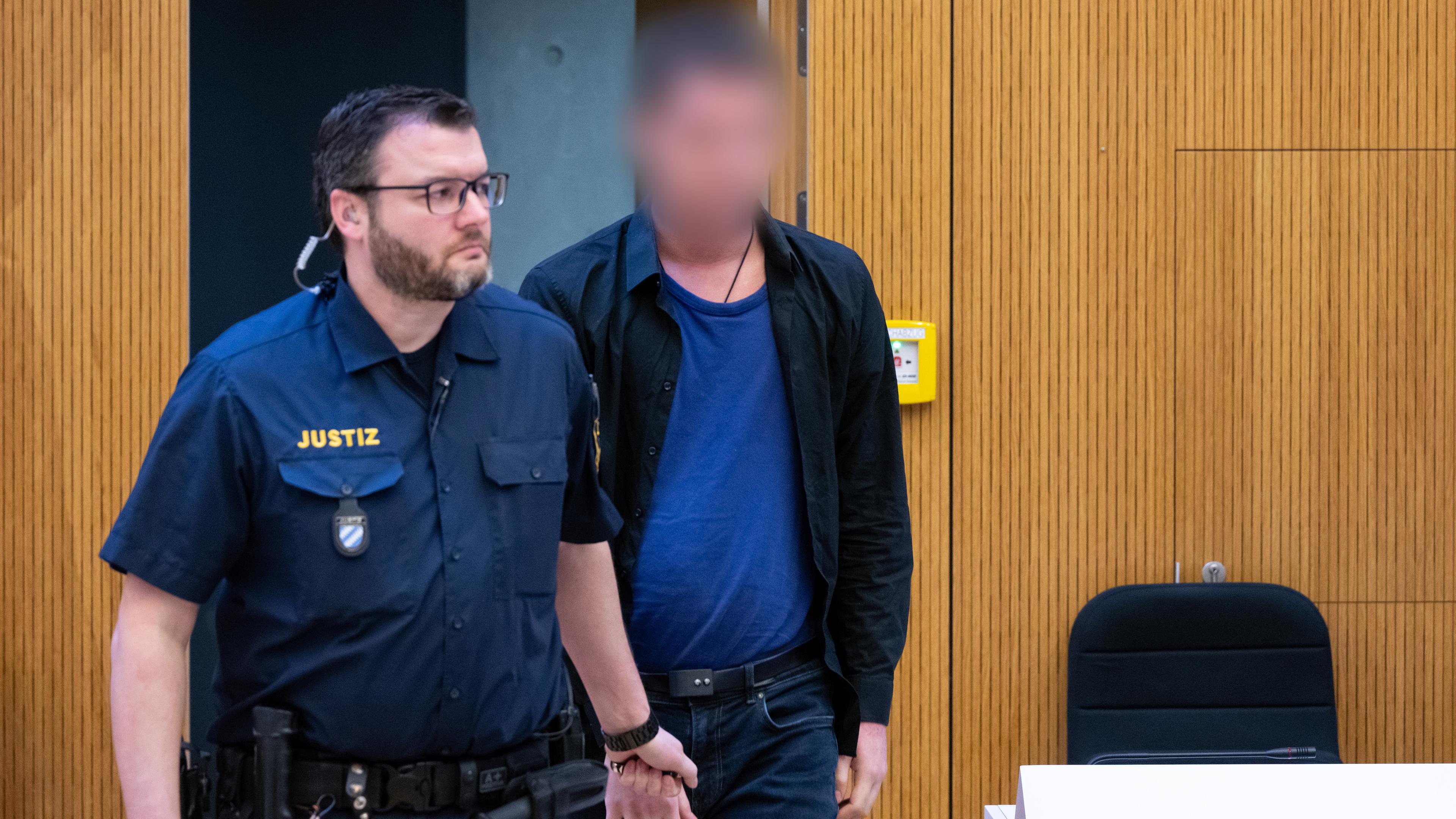 Bayern, München: Einer von zwei wegen Mordes angeklagten Männern (r) wird vor Beginn der Verhandlung in den Hochsicherheitsgerichtssaal vom Landgericht München II geführt.