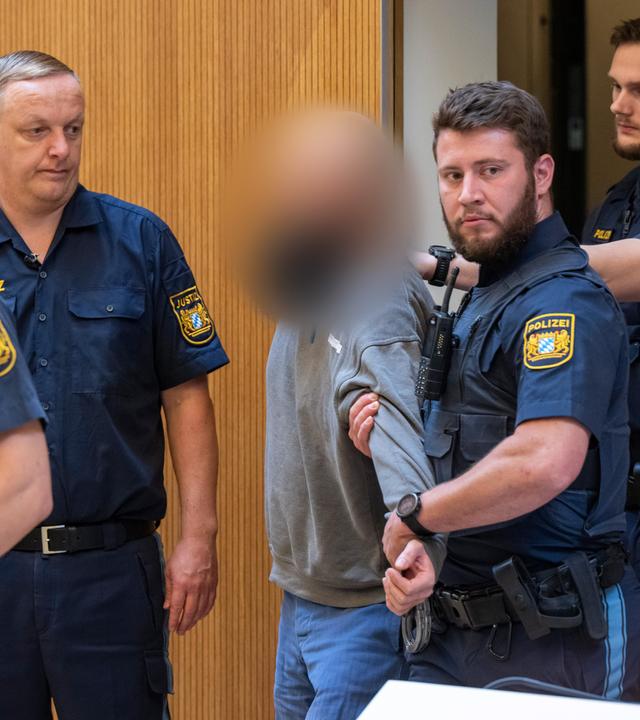 Bayern, München: Ein Angeklagter (M) wird zu Beginn des Prozesses gegen ein deutsch-russisches Trio wegen Geheimdiensttätigkeit für Russland und Mitgliedschaft in einer ausländischen Terrorgruppe in den Gerichtssaal geführt.