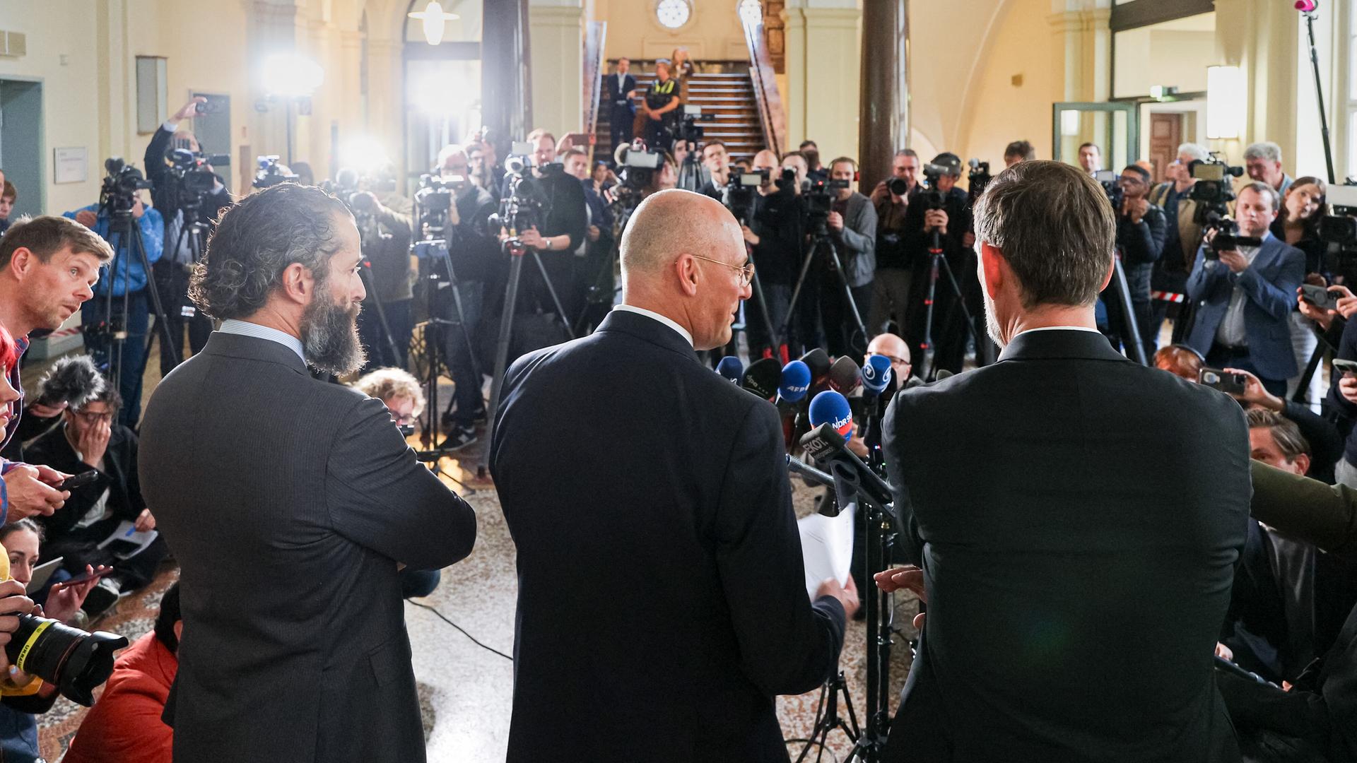  Die Verteidiger des Angeklagten, Nicola Canestrini (l-r), Jes Meyer Lohkamp und Lars Brögeler, sprechen nach Abschluss des ersten Prozesstags zu Pressevertretern.