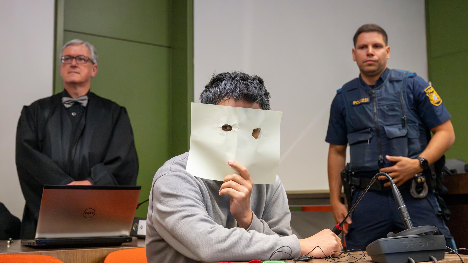 Bayern, München: Der Angeklagte sitzt zum Prozessauftakt auf seinem Platz im Gerichtssaal des Landgerichts München und verdeckt sein Gesicht. 