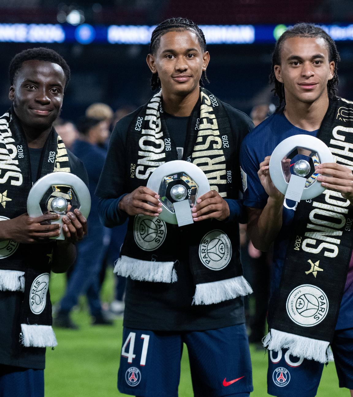 Die PSG-Spieler Yoram Zague, Senny Mayulu und Ethan Mbappe (von links) zeigen nach dem Gewinn der französischen Meisterschaft eine Trophäe am 12. Mai 2024