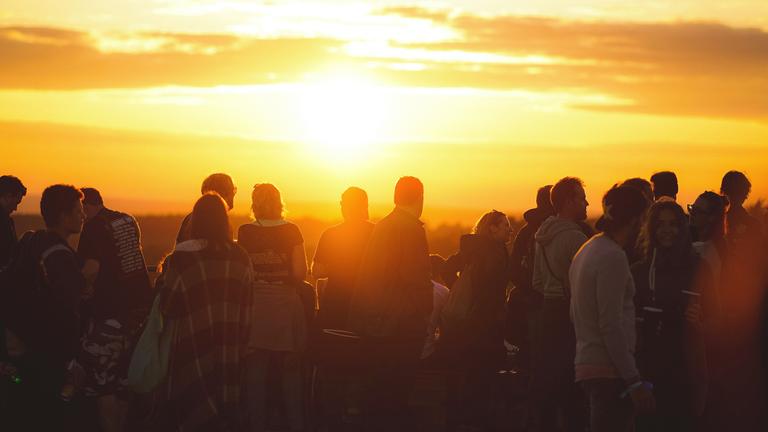 Typical für Public Value in ZDF-Programmen: Menschengruppe im schattigen Vordergrund vor einem gelbleichen Sonnenuntergang