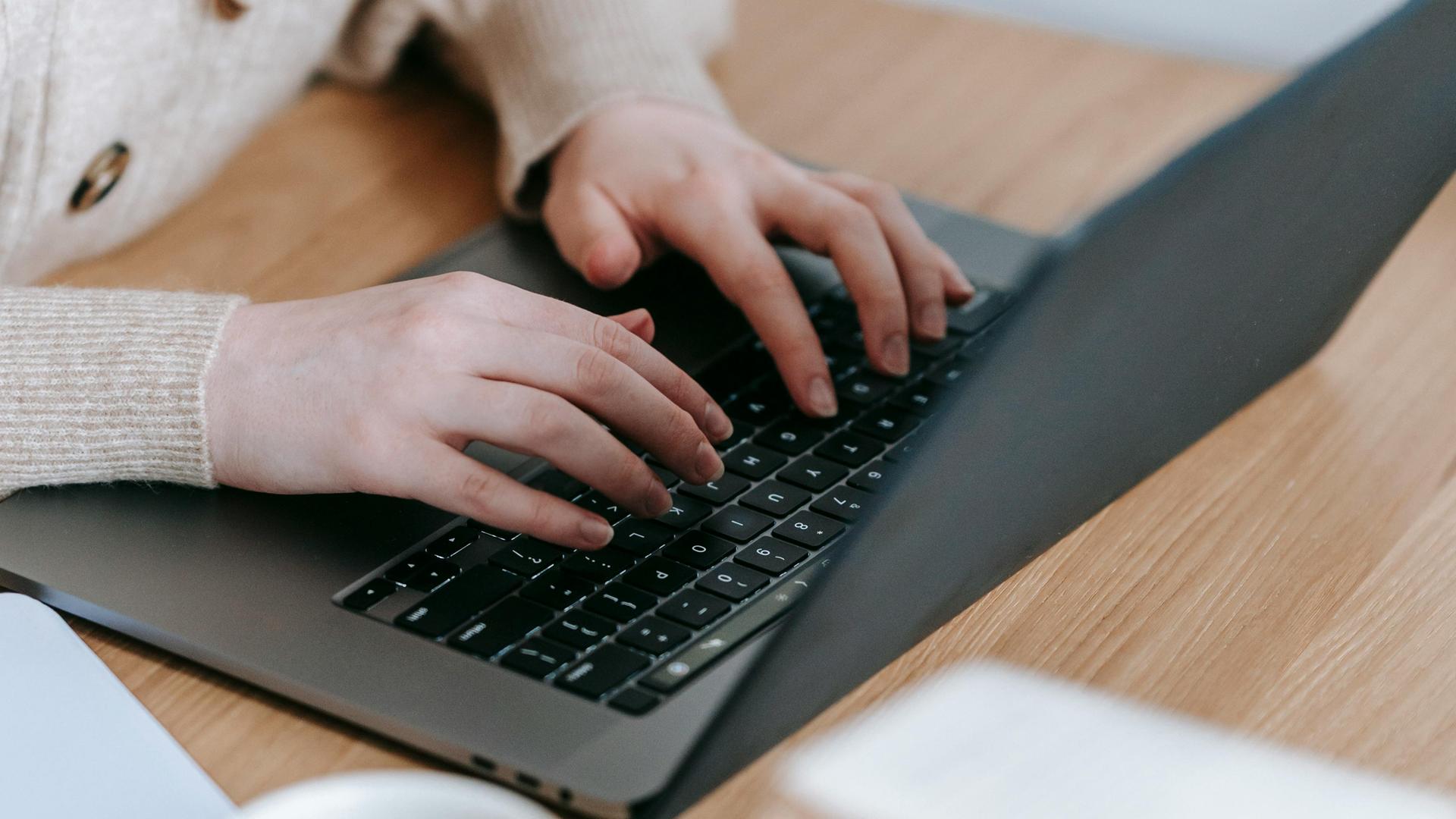 Frauenhände Tippen auf die Tastatur eines Laptops