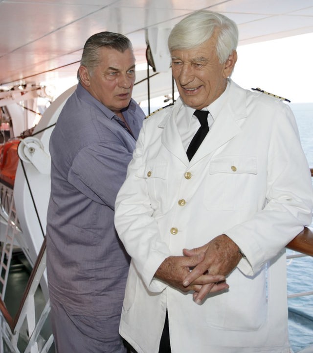 "Das Traumschiff: Puerto Rico": Paul (Heinz Hoenig) steht an der Reling der MS Amadea und blickt fragend Kapitän Paulsen (Siegfried Rauch) an. Dieser lächelt und hält die Hände gefaltet.