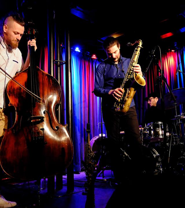 Zwei Musiker mit Kontrabass und Klarinette spielen auf einer blau und lila angeleuchteten Bühne.