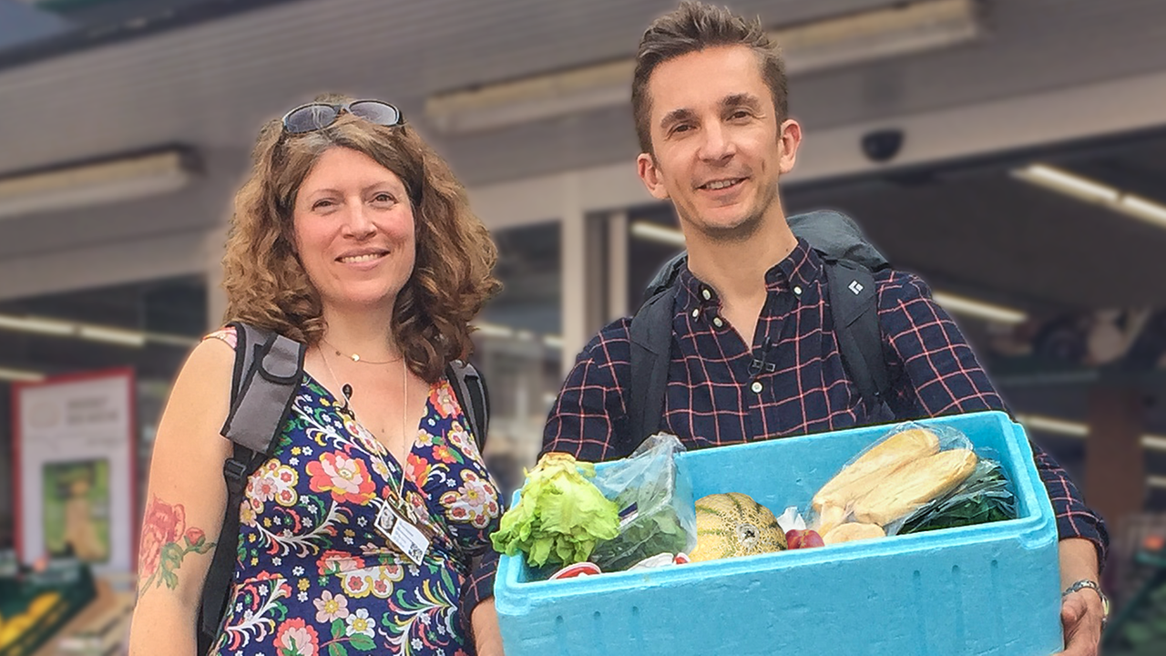 Moderator Eric (rechts) und eine Foodsaverin (links) halten eine Kühlbox gefüllt mit geretteten Lebensmitteln in die Kamera.