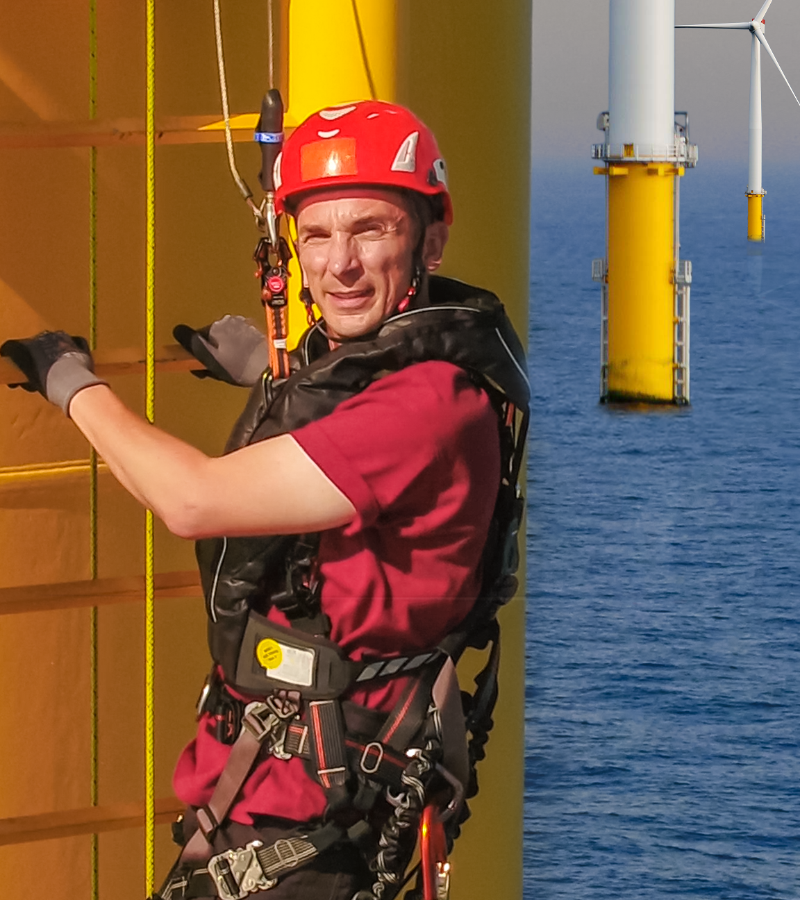 Reporter Eric mit Helm auf der Leiter eines Windrades in der Nordsee.