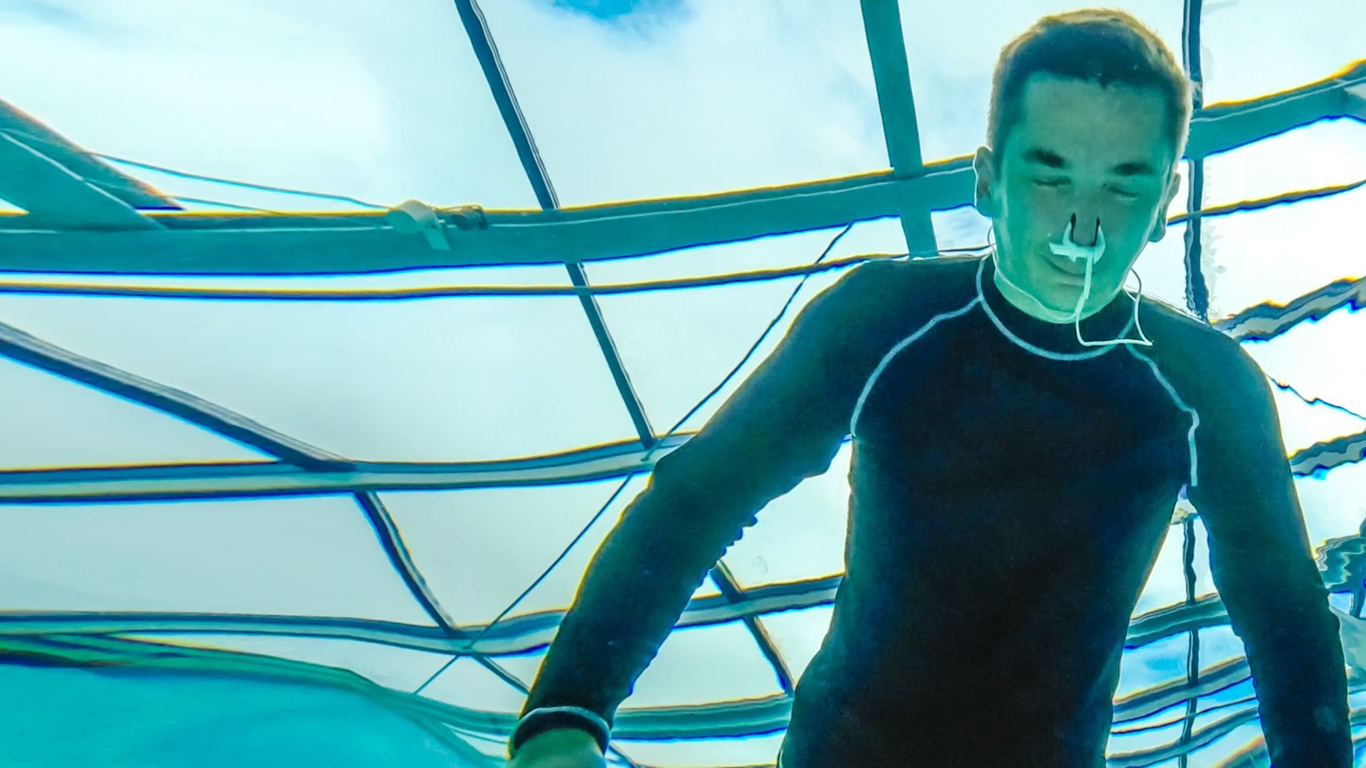 PUR+ Moderator Eric Mayer trainert in einem Neoprenanzug das Luftanhalten unter Wasser. Die Aufname zeigt ihn unter Wasser aus, wie er mit dem Gesicht unter Wasser und geschlossenen Augen sich aufs Luftanhalten konzentriert.