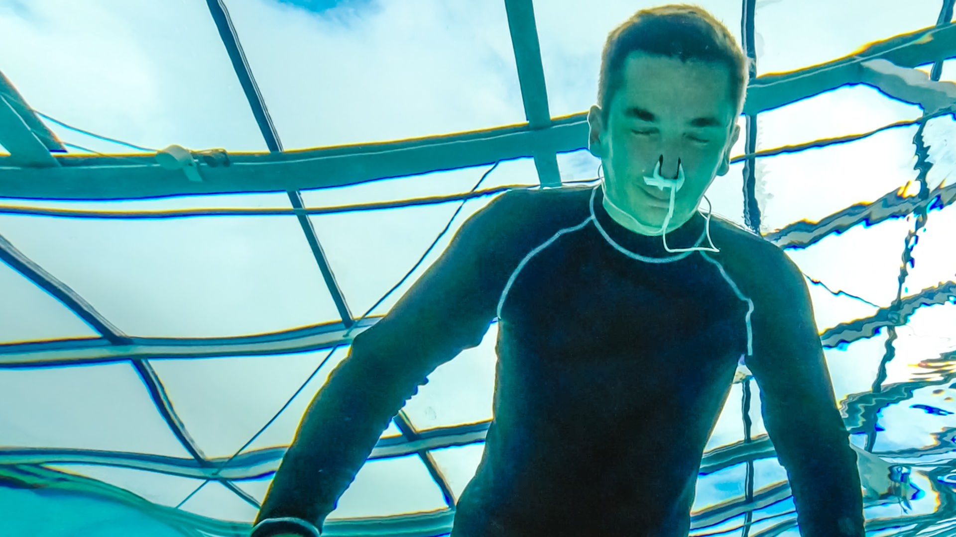 PUR+ Moderator Eric Mayer trainert in einem Neoprenanzug das Luftanhalten unter Wasser. Die Aufname zeigt ihn unter Wasser aus, wie er mit dem Gesicht unter Wasser und geschlossenen Augen sich aufs Luftanhalten konzentriert.
