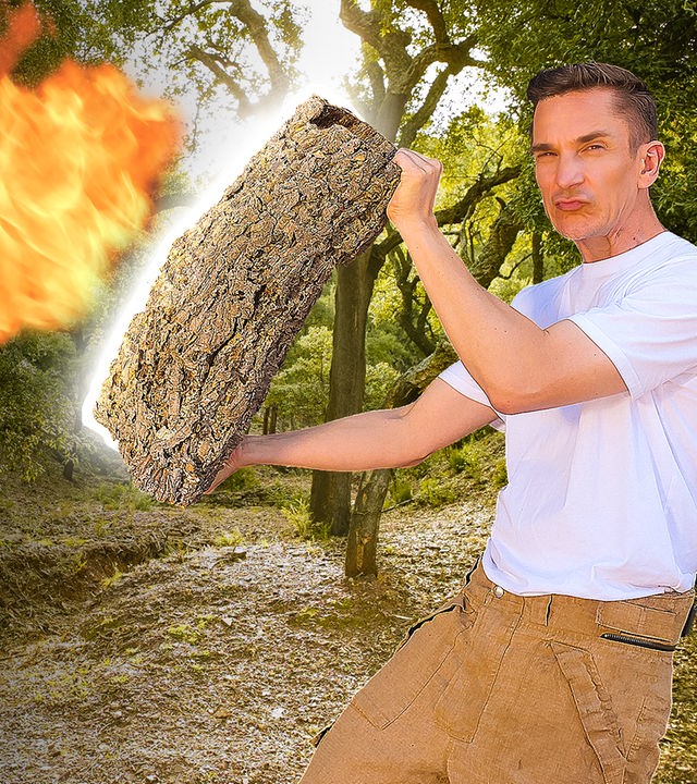 Moderator Eric Mayer hält ein großes Stück Korkeiche in den Händen und hält es einem Flammenwerfer entgegen, aus dem eine große Flamme schlägt.