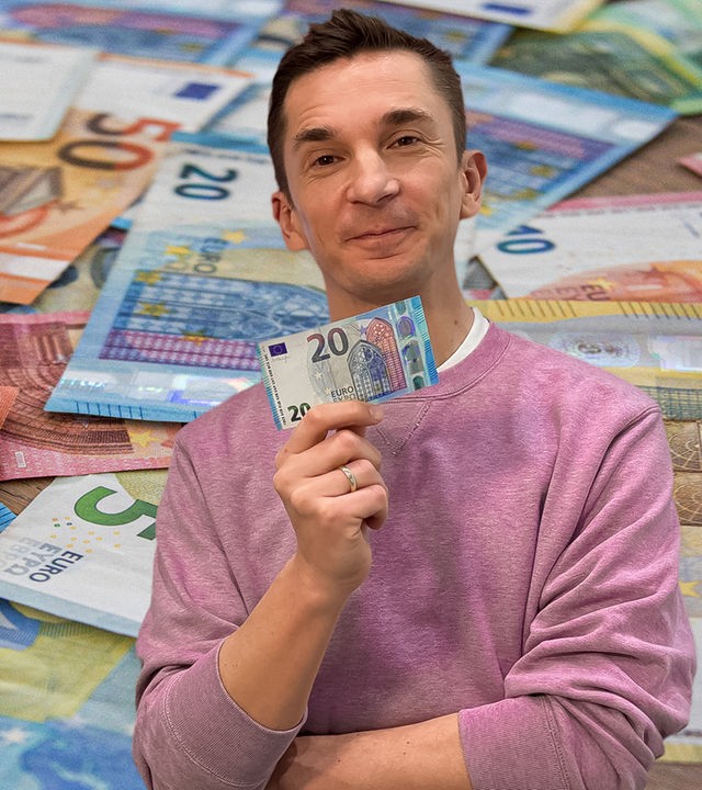 Eric hält einen 20€-Schein in die Kamera, hinter im sieht man verschiedene Geldscheine.