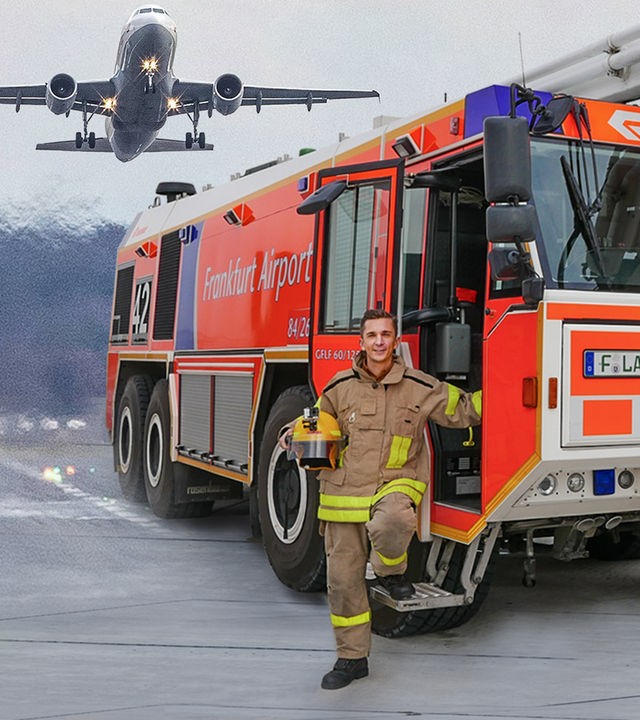 Moderator Eric trägt eine Feuerwehr-Uniform und steht vor einem Einsatzfahrzeug auf einem Flugfeld. Im Hintergrund fliegt ein Flugzeug am Himmel.