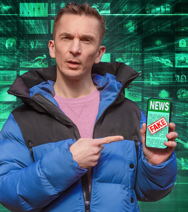 Eric trägt eine blaue Daunenjacke und darunter einen rosafarbenen Pulli. Er hält ein Smartphone in seiner linken Hand. Auf dem Display sieht man das Wort "News" und darüber ist ein roter Fake-Stempel. Im Hintergrund sind viele kleine Bilder in kleinen Kacheln zu sehen, die verschiedene Fakemotive darstellen sollen.