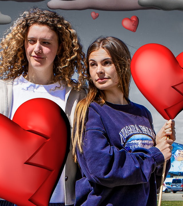 Angelina (links) und Emma (rechts) aus der Sendug "Mädchen WG" stehen nebeneinander und schauen ernst in die Ferne. Beide halten mit einer Hand einen gezeichneten Herzluftballon. Beide Herzballons sind in der Mitte in zwei Teile gerissen, die durch eine Zackenlinie getrennt sind. Im Hintergrund sind gezeichnete graue Wolken zu sehen.
