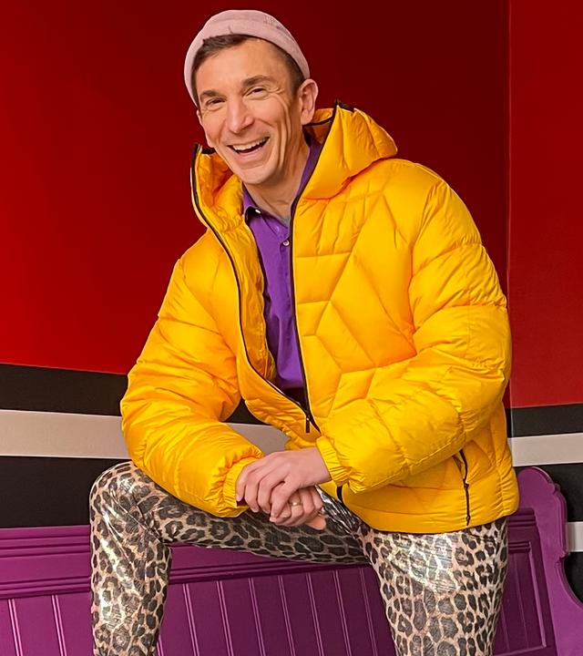 PUR+ Moderator Eric in seinem beuen Look mit gelber Jacke, Leoprint-Hose und Mütze
