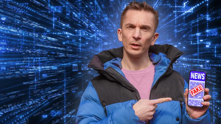 Eric trägt eine blaue Daunenjacke und darunter einen rosafarbenen Pulli. Er hält ein Smartphone in seiner linken Hand. Auf dem Display sieht man das Wort "News" und darüber ist ein roter Fake-Stempel.