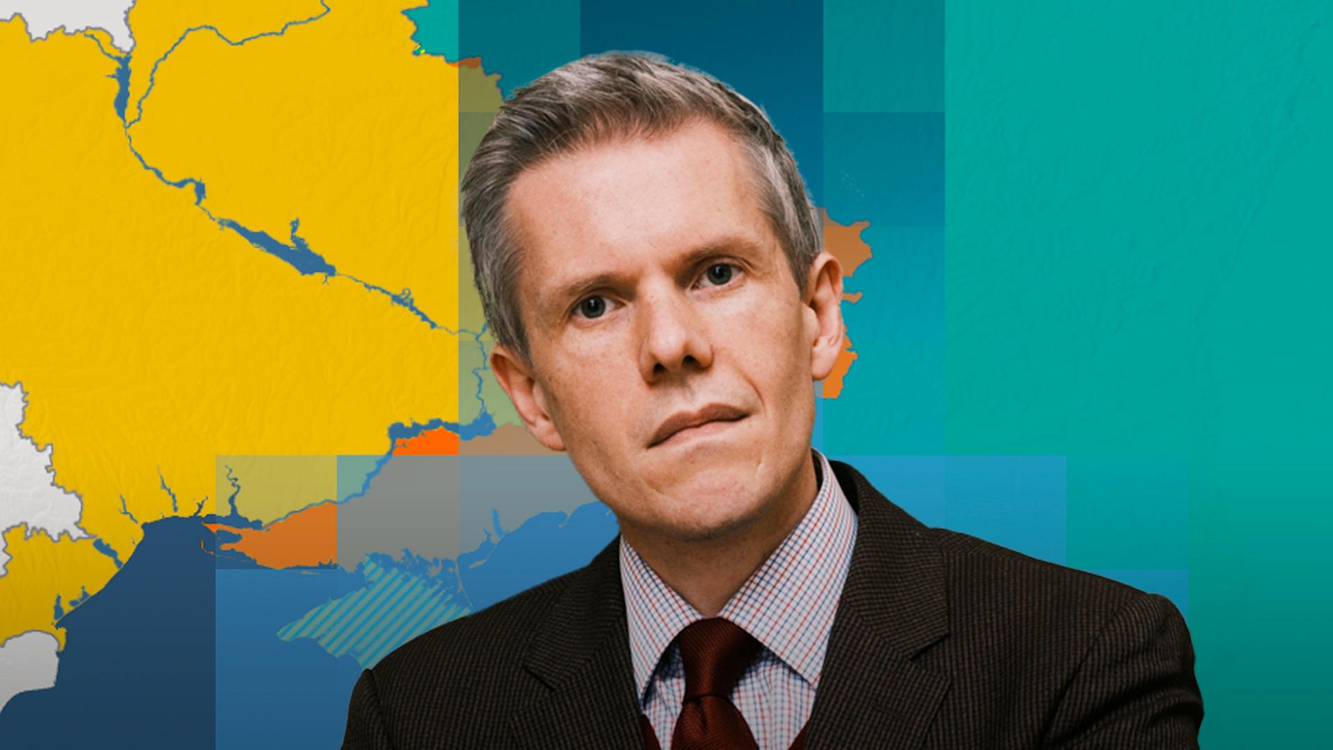 Militärökonom Markus Keupp ist vor einer Karte der Ukraine mit aktuellem Frontverlauf abgebildet.