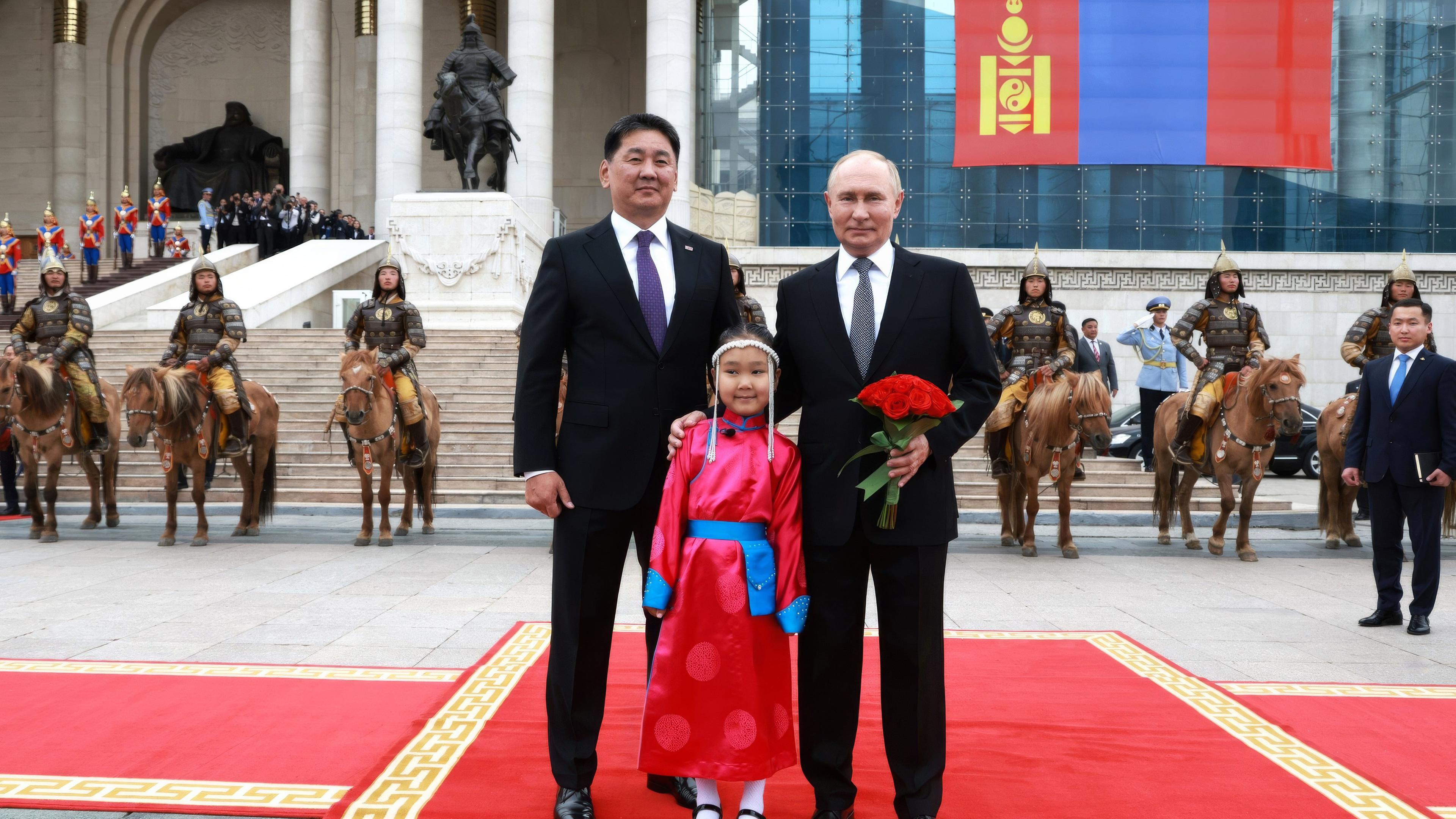 Archiv: Der russische Präsident Wladimir Putin (r.) posiert mit dem mongolischen Präsidenten Uchnaagiin Chürelsüch und einem jungen Blumenmädchen während der Ankunftszeremonie im Regierungspalast auf dem Suchbaatar-Platz am 3. September 2024 in Ulan Bator, Mongolei