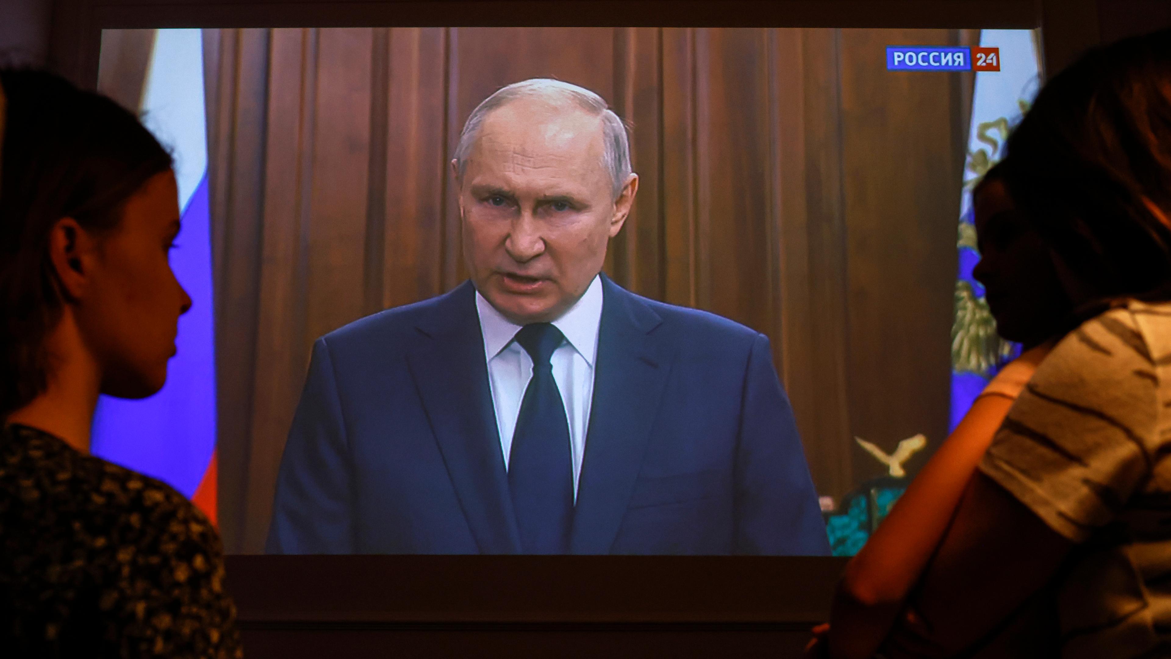 Russlands Präsident Putin spricht im Fernsehen, Menschen schauen zu
