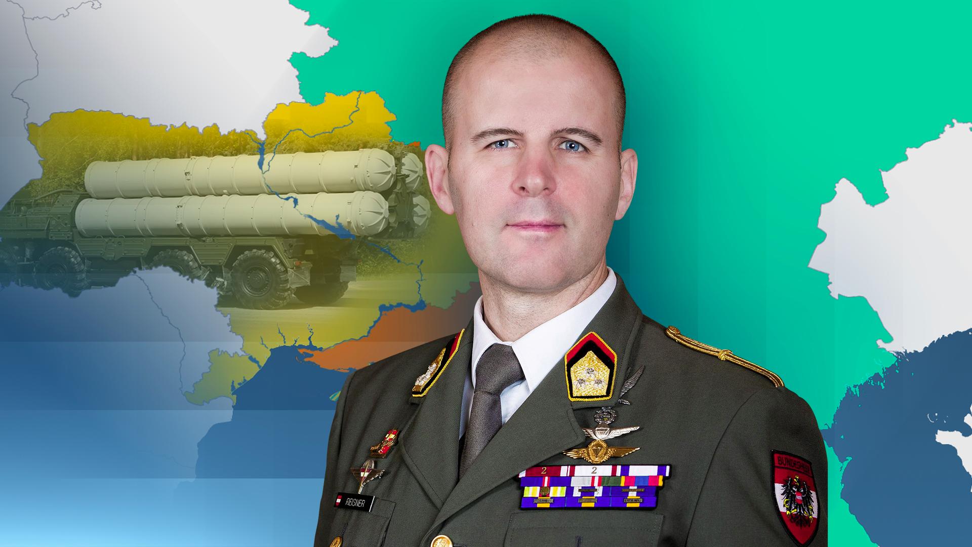 Oberst Reisner ist in seiner Uniform vor einer Karte der Ukraine zu sehen. Im Hintergrund sind Oreschnik-Raketen zu sehen.