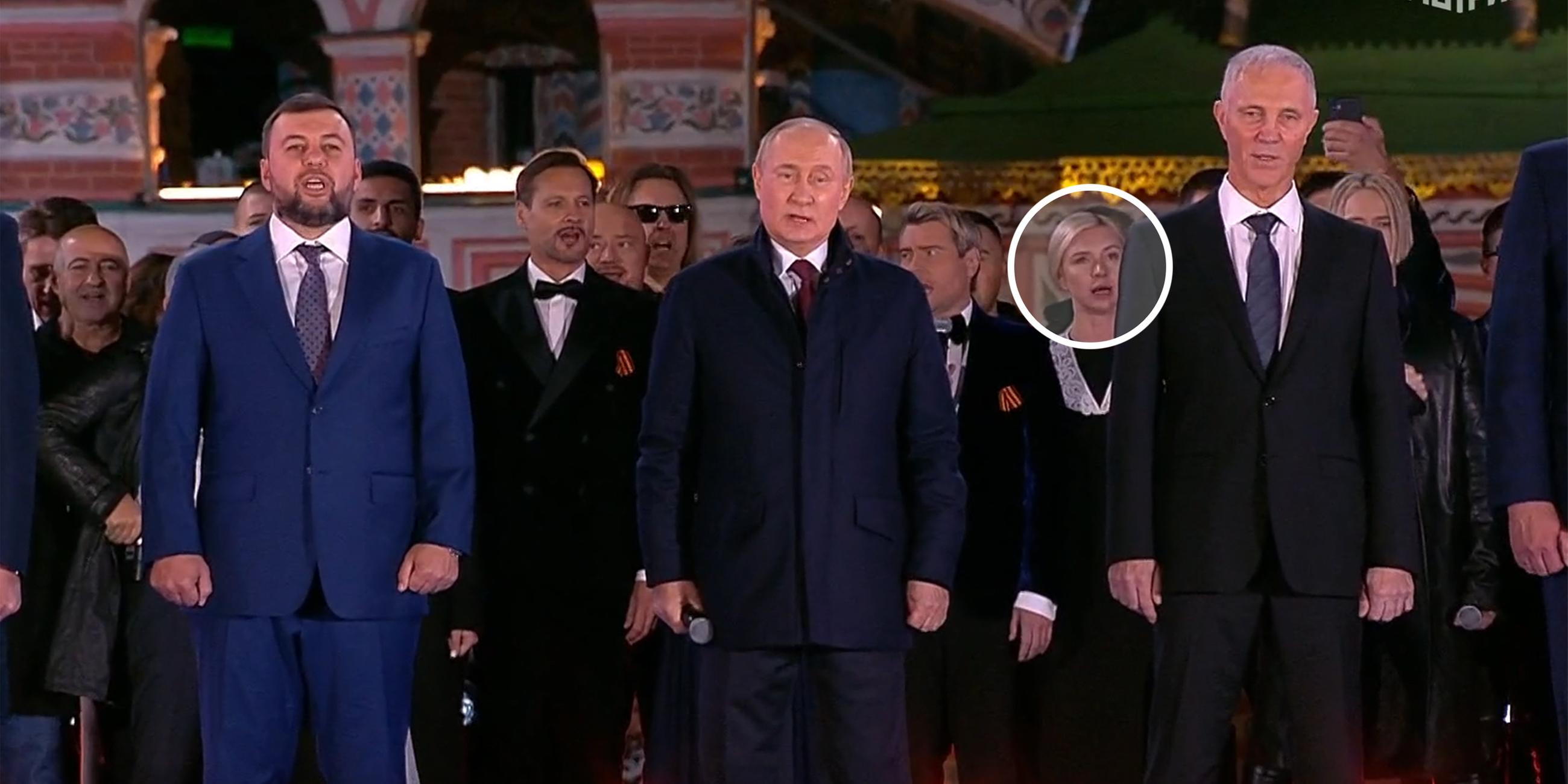 Wladimir Putin singt auf einer Bühne die Nationalhymne