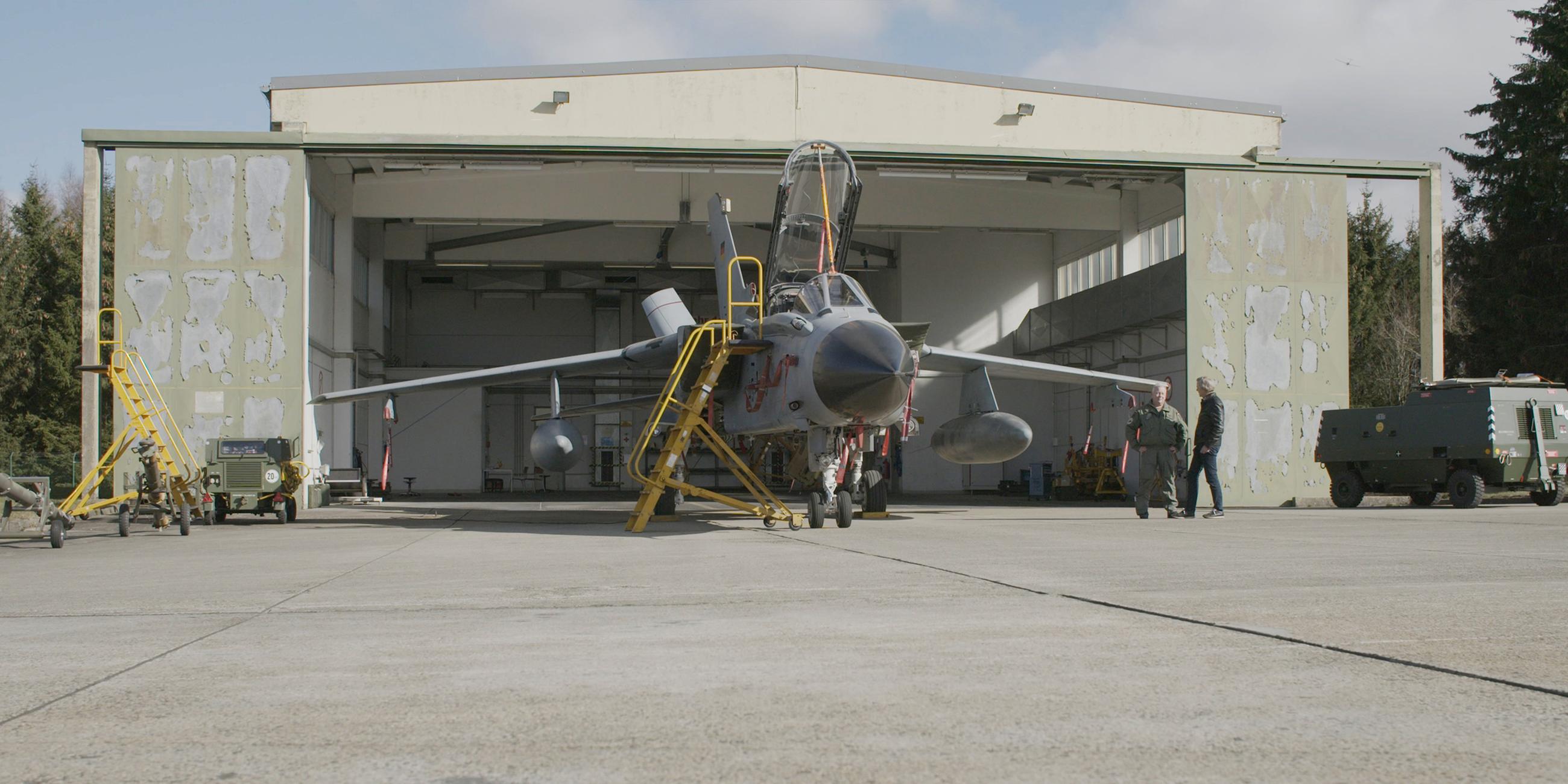 Ein Kampflugzeug steht vor einem Hangar.