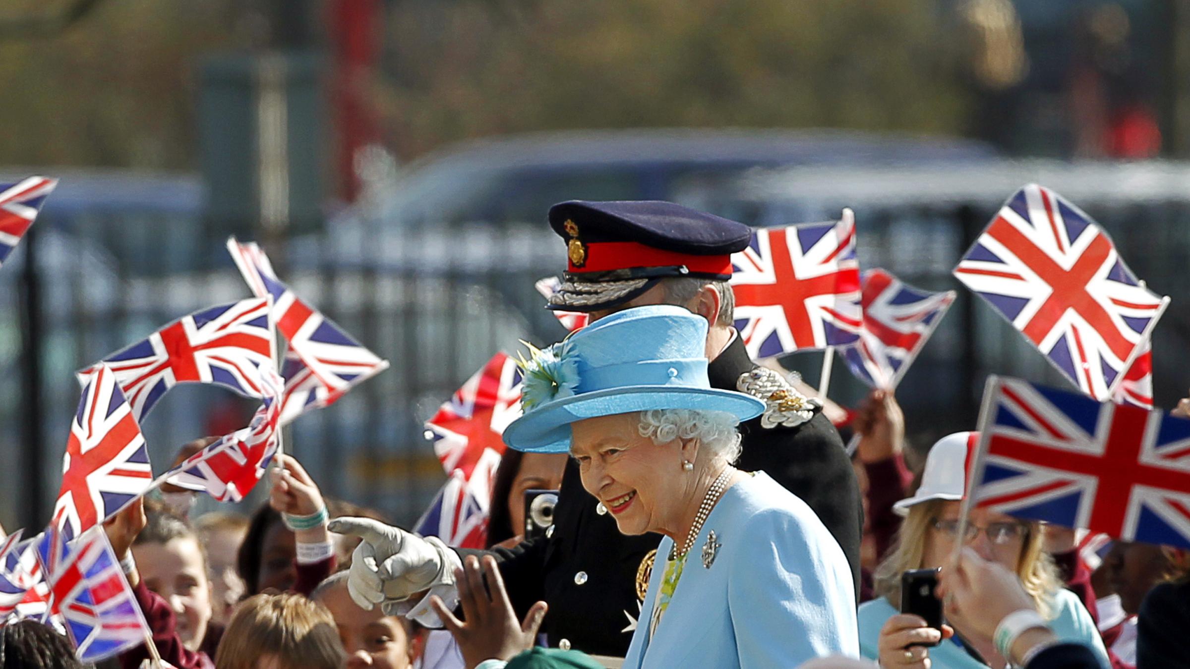 Königin Elizabeth umringt von jungen Anhängern, die britische Fähnchen schwenken.