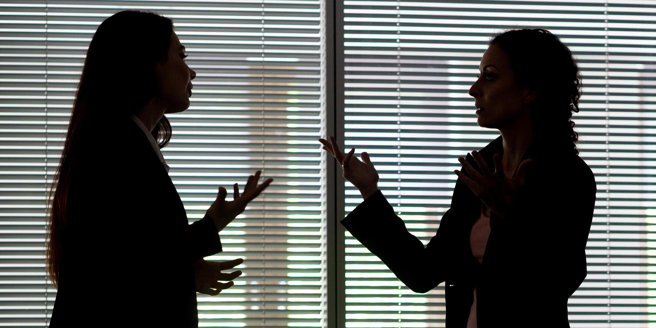 Zwei Frauen heben gestikulierend die Hände in die Höhe, während sie diskutieren.