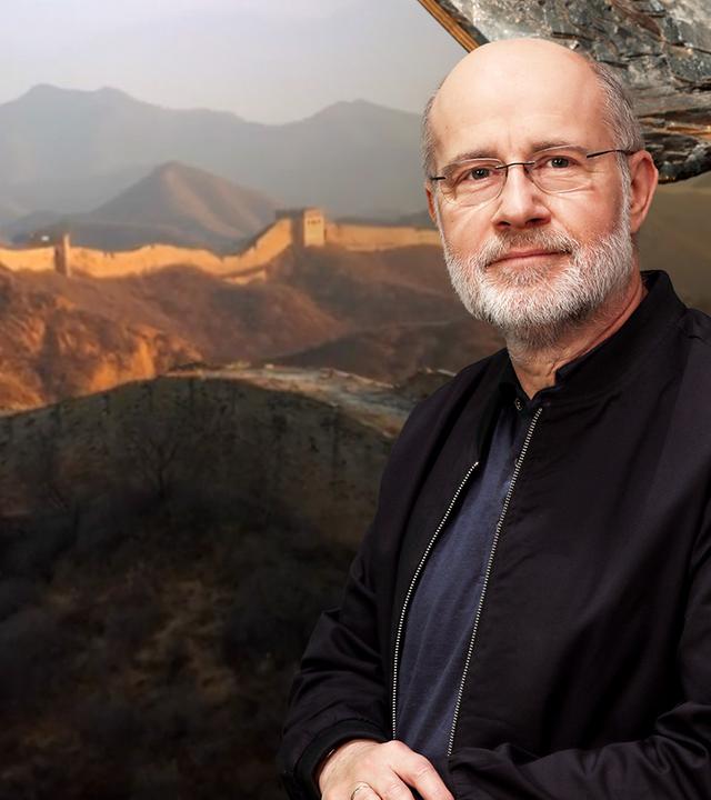 Harald Lesch schaut in die Kamera, links im Hintergrund ist die chinesische Mauer zu sehen.