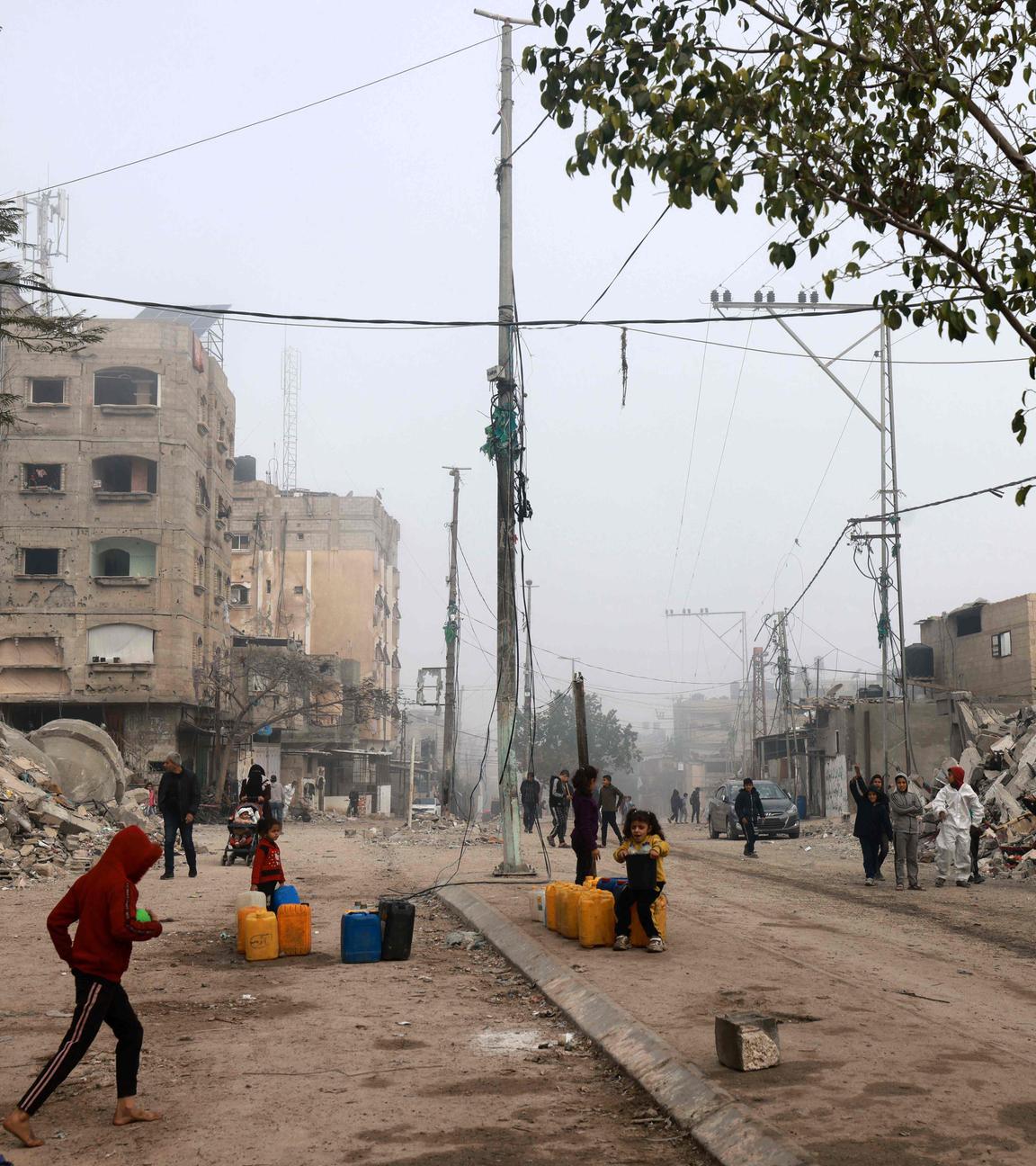 Kinder füllen Kanister mit Wasser inmitten von Gebäuden, die durch israelisches Bombardement in Rafah am 25. Februar 2024 dem Erdboden gleichgemacht wurden.