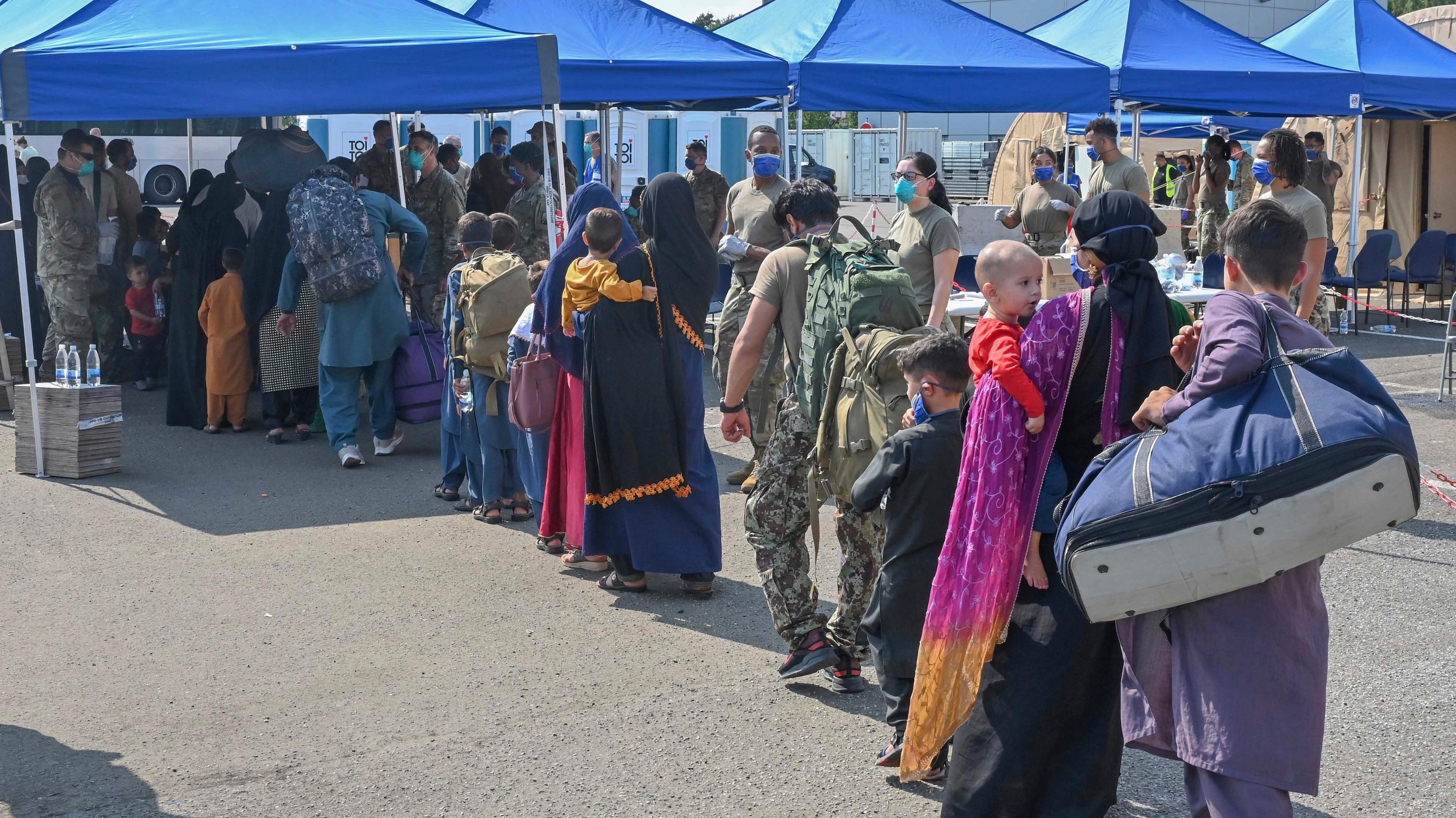 Afghanische Flüchtlinge, die aus Kabul evakuiert wurden, stellen sich nach ihrer Ankunft auf der Air Base Ramstein zur Abfertigung auf. (Archivbild)