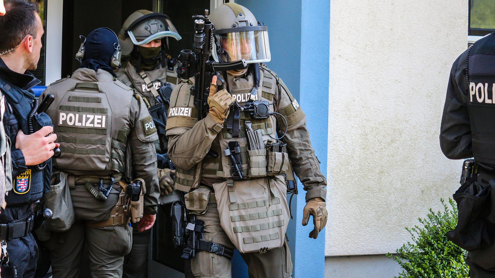 SEK- und Polizeibeamte stehen am Eingang eines Wohnhauses. 
