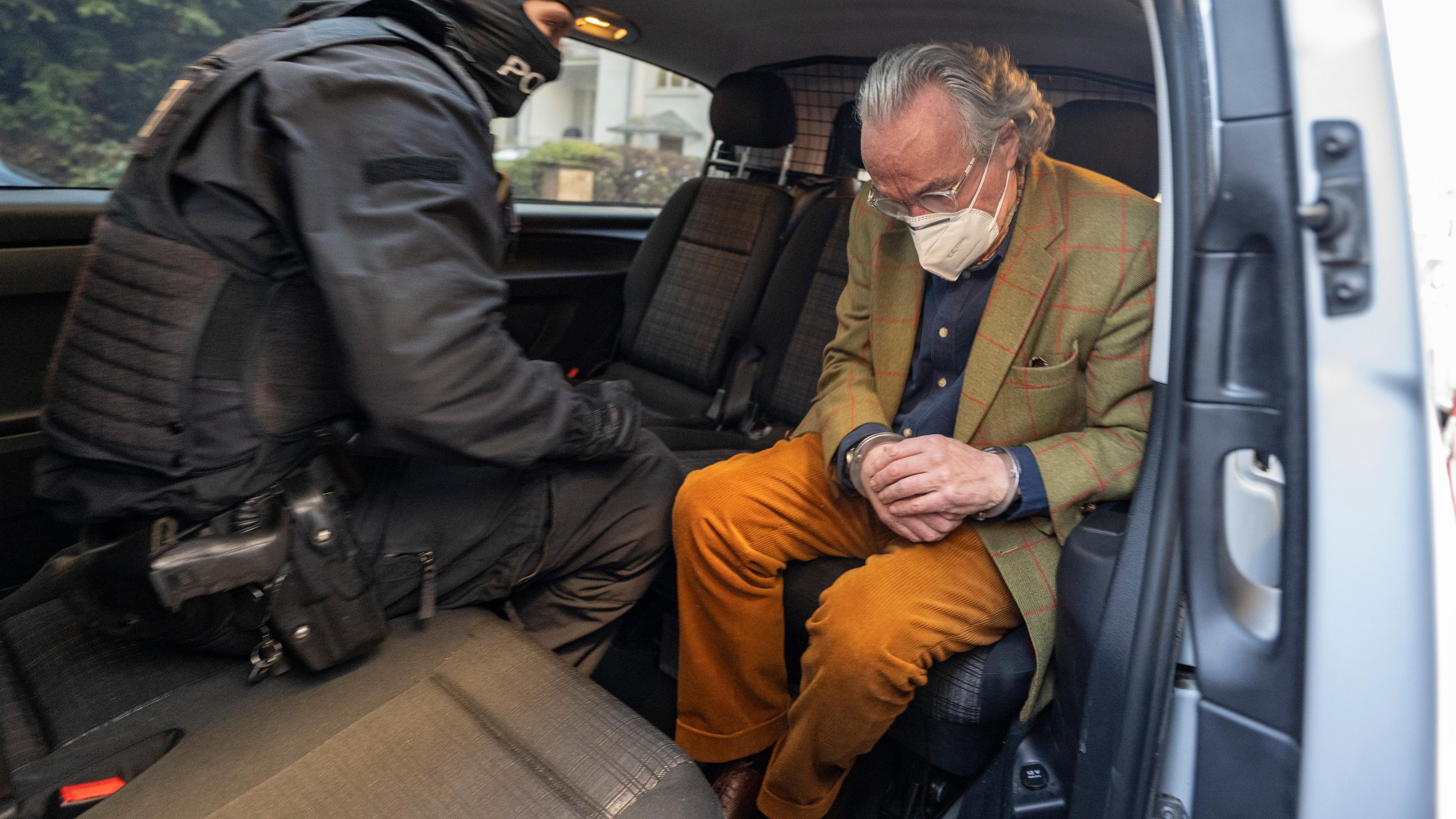 Bei einer Razzia gegen sogenannte «Reichsbürger» sitzt ein vermummter Polizist, nach der Durchsuchung eines Hauses, mit dem festgenommenen Heinrich XIII Prinz Reuß (r) in einem Polizeifahrzeug. Dieser trägt dabei Handschellen.