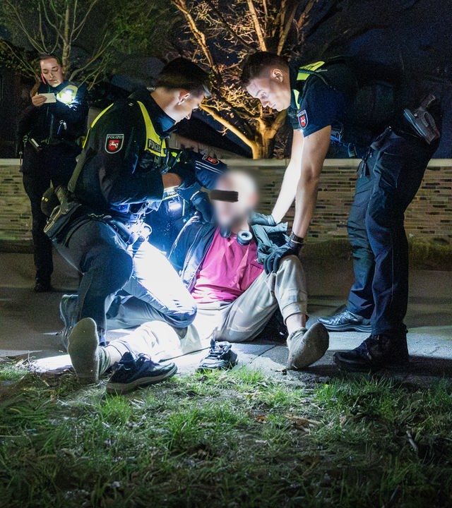 Zwei Polizisten halten auf einer Wiese einen Mann am Boden.