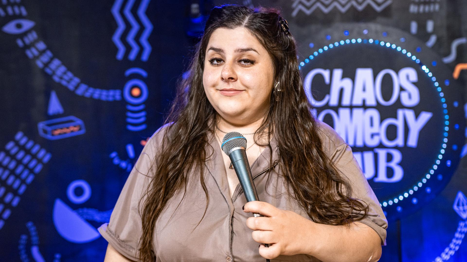 Rebecca Pap ist in der Mitte des Bildes zu sehen. In ihrer linken Hand hält sie ein Mikrofon.