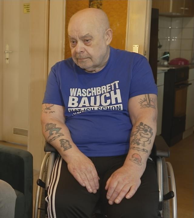 Rechtliche Betreuerin (links) sitzt auf einer Couch und der rechtlich Betreute (rechts) sitzt im Rollstuhl daneben.