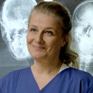 Rechtsmedizinerin Dr. Franziska Sommerfeld (Christina Rainer) an ihrem Arbeitsplatz. Im Hintergrund hängen Röntgenaufnahmen eines Kopfes.