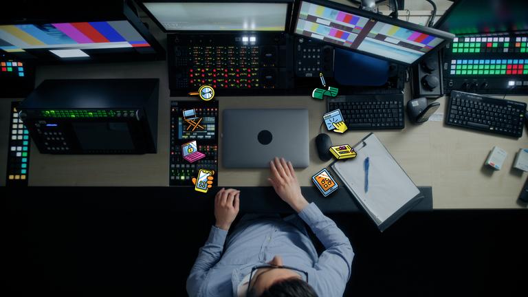 Auf dem Bild ist ein Laptop zu sehen, aus dem kleine Icons fliegen, die mit dem Redaktionsvolontariat zu tun haben: Ein Handy, ein Notizblock, ein Regiestuhl usw.