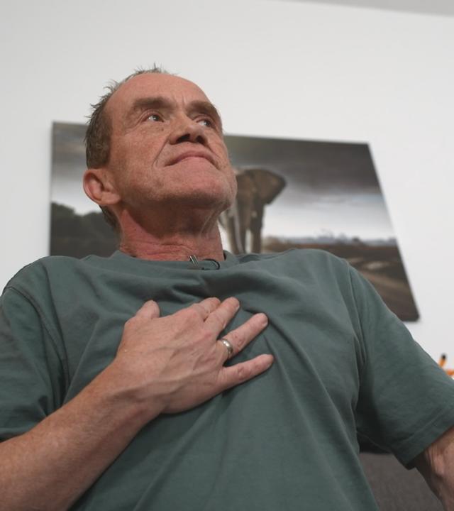 Mann hält sich Hand an die Brust