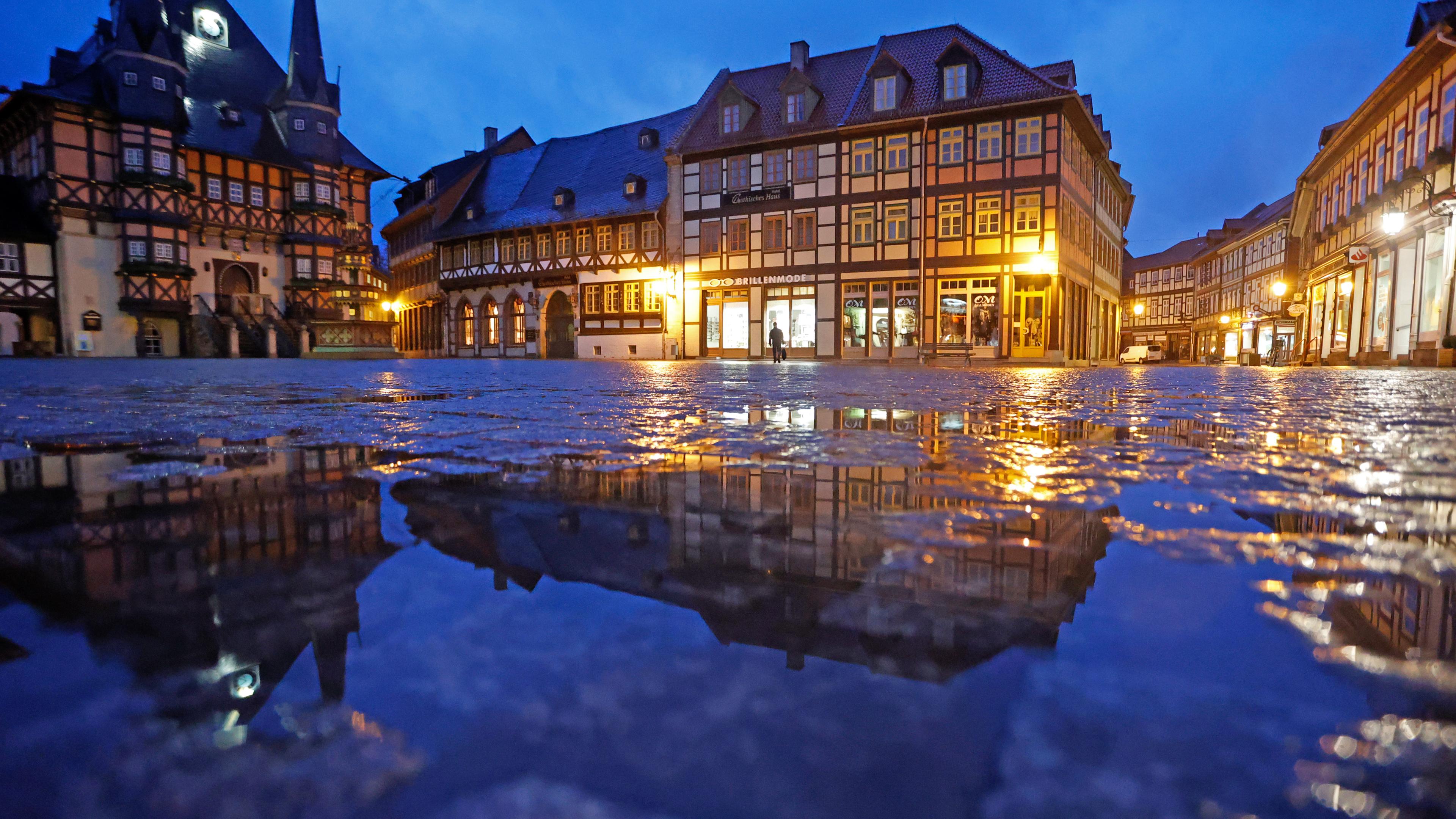 Sachsen-Anhalt, Wernigerode: Das Rathaus in Wernigerode spiegelt sich am frühen Morgen in einer Regenpfütze auf dem Marktplatz