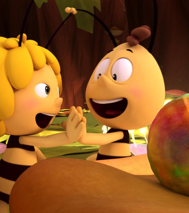 Maja und Willi freuen sich sehr über den besonderen Pollenball, den sie zusammengetragen haben. Sie geben sich ein High Five, während der große Pollenball grünlich schimmert.