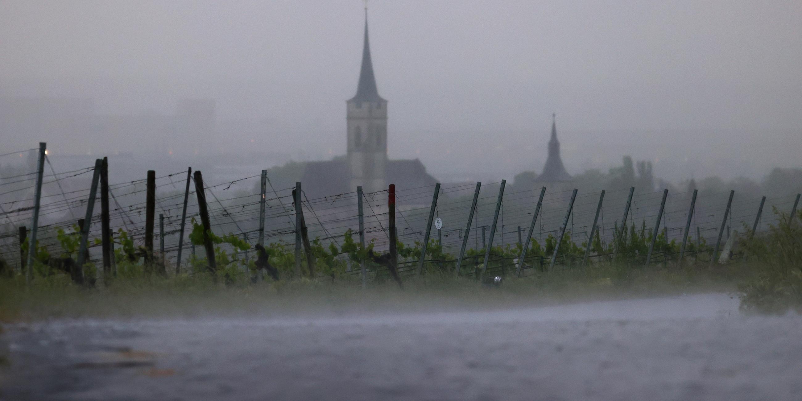 Im Starkregen liegen die Weinberge am Schwanberg vor dem Kirchturm des Ortes.