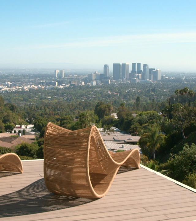 Zwei Liegestühle stehen auf einer Terrasse mit Blick auf Skyline von Los Angeles.