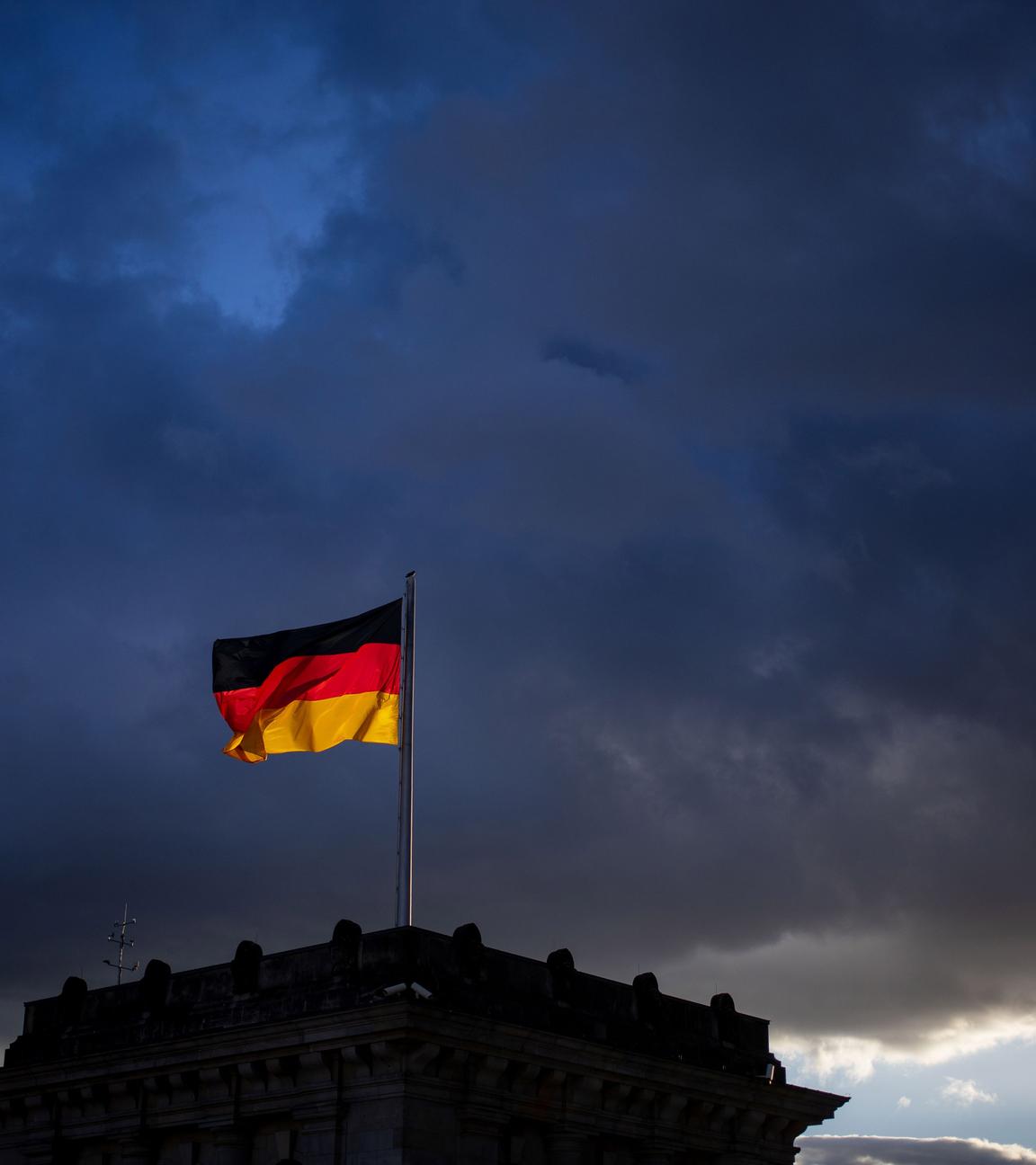 Archiv: Eine Deutschlandflagge weht über dem Bundestag vor den dunklen wolken im wind. 