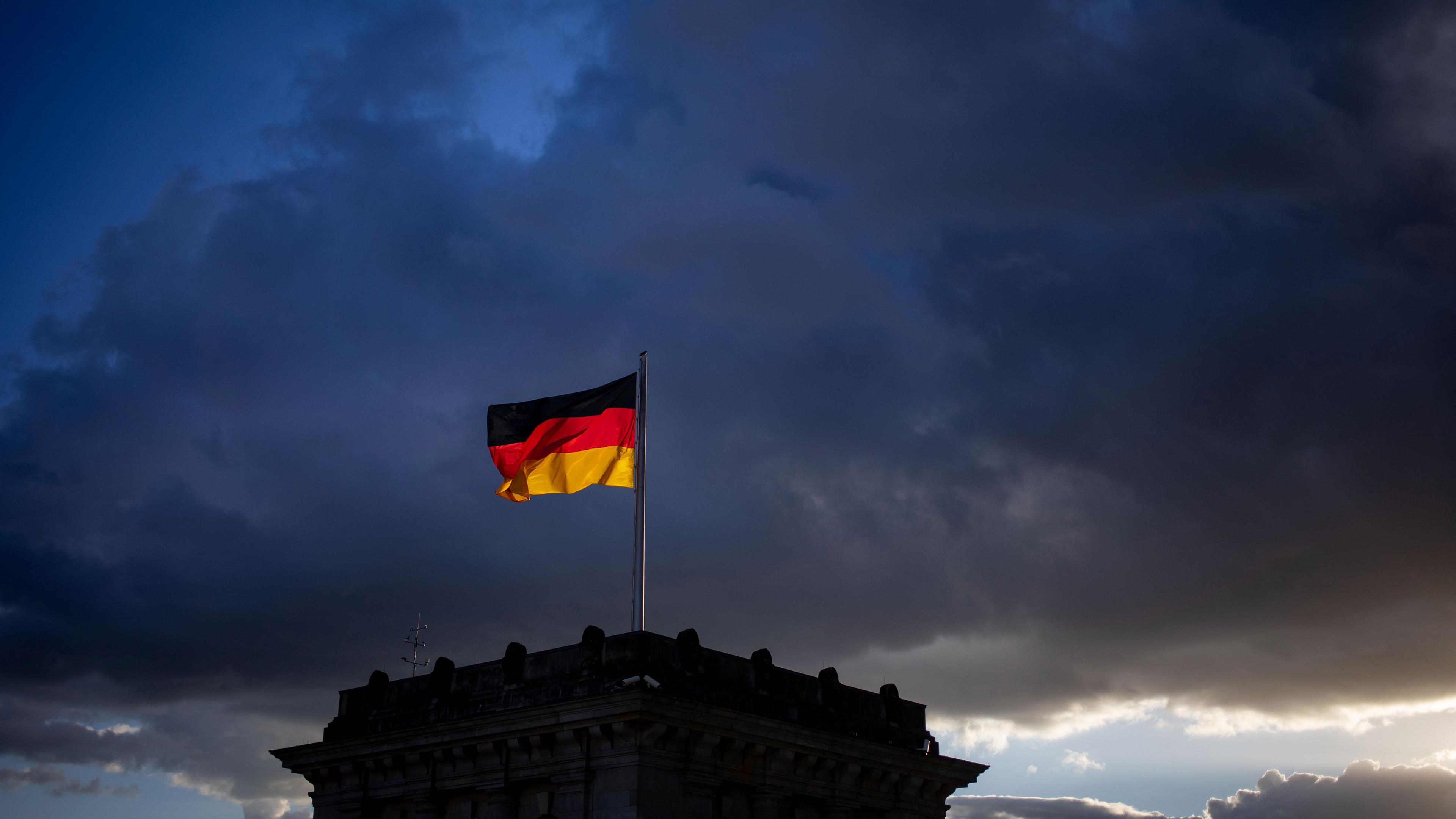 Archiv: Eine Deutschlandflagge weht über dem Bundestag vor den dunklen wolken im wind. 