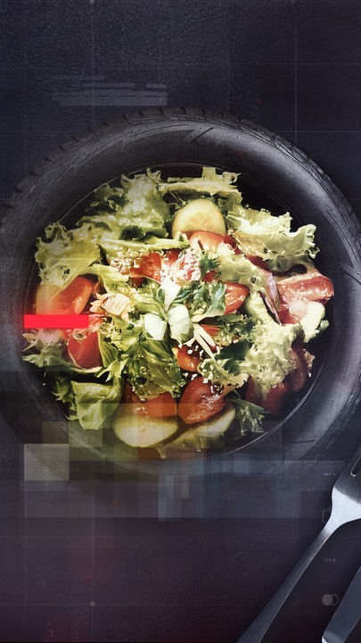 Reifen, der einen Teller darstellt und auf dem Salat liegt, rechts und links davon Messer und Gabel