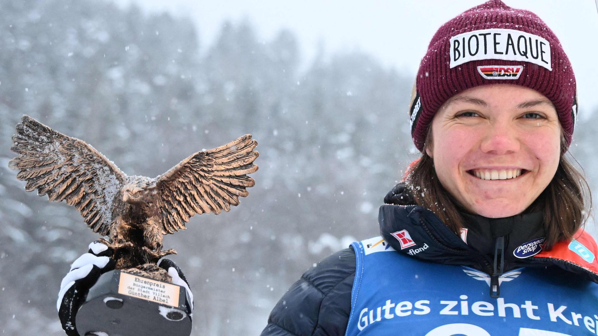 Agnes Reisch hält die Trophäe für ihren dritten Platz beim Skispringen in Villach in der rechten Hand.